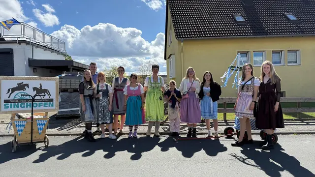 Gruppe in Dirndl und Tracht vor einem Gebäude